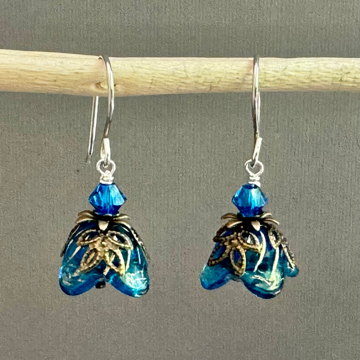 Blue Czech glass earrings with floral designs on a gray background
