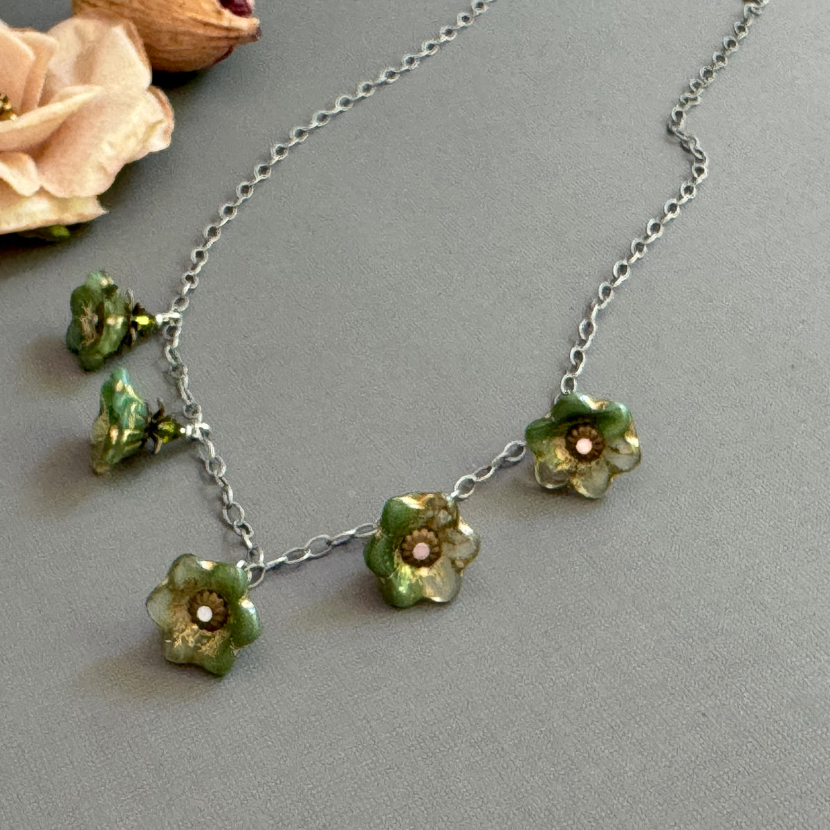 Necklace with green floral glass beads on a gray background