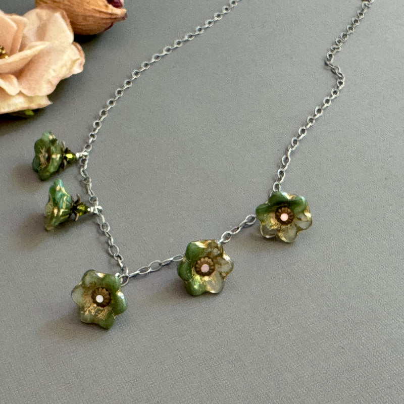 Necklace with green floral glass beads on a gray background