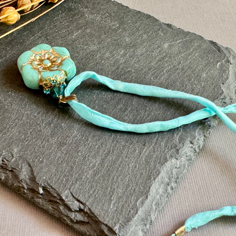 Light Teal Czech Glass Flower Pendant Necklace on Silk Cord in Antique Brass
