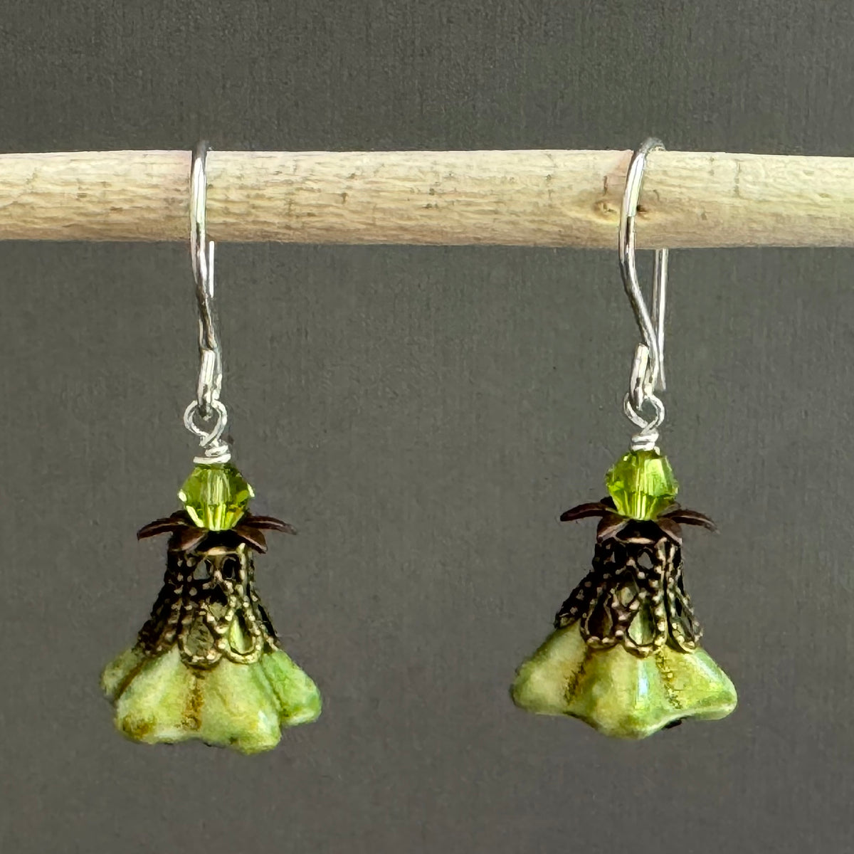 Pair of green flower-shaped earrings with antique brass components. 